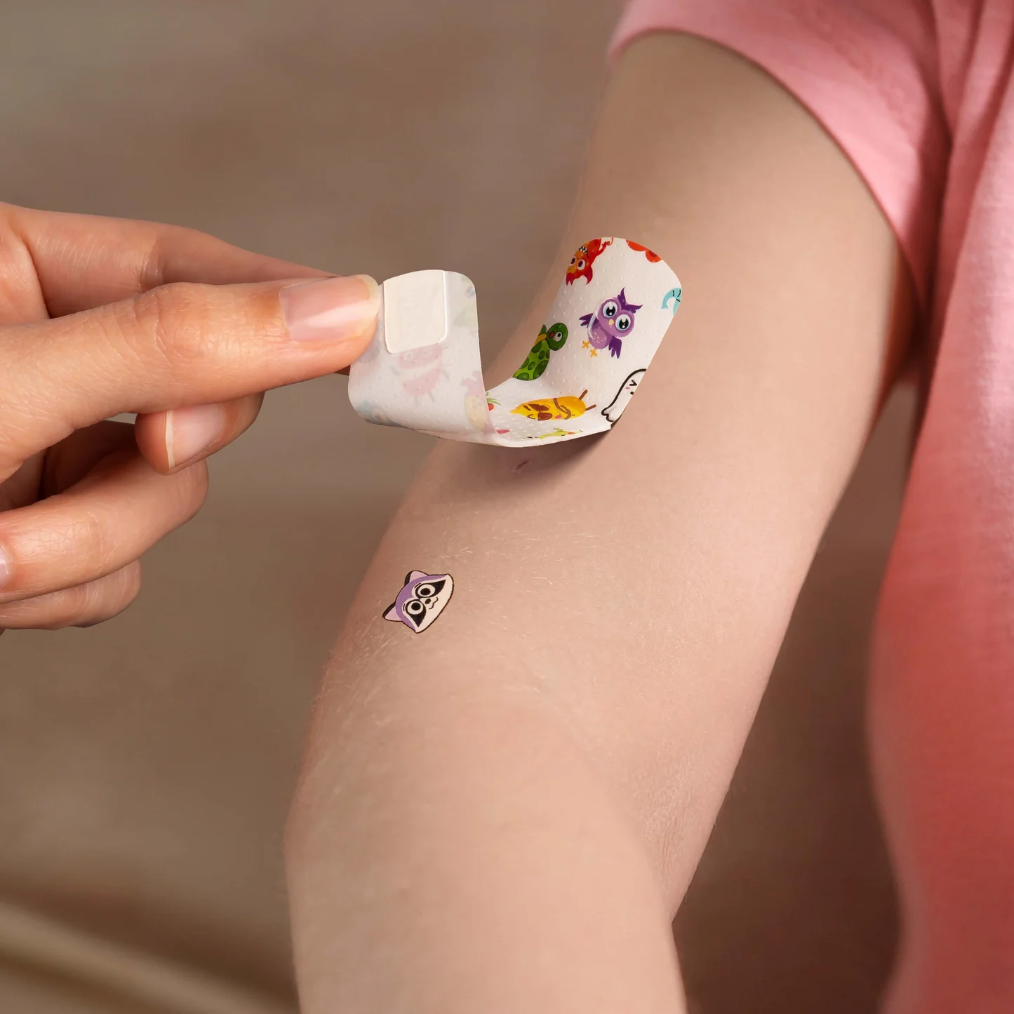A parent peeling a Brandage bandage off a child's arm, revealing a small tattoo left behind on the skin.